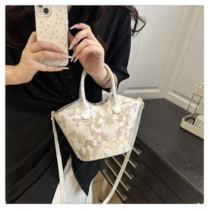 Detail of embroidered floral handbag with gold patterns shown being held by a model