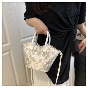 Gros plan d'une élégante broderie florale sur un sac à main trapèze blanc avec anses