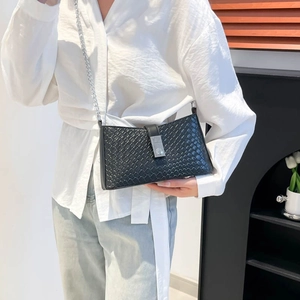 Women's black woven crossbody bag with silver chain strap shown on model's shoulder