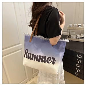 Detail of a gradient canvas tote bag with Summer print, fringe edges, and leather straps