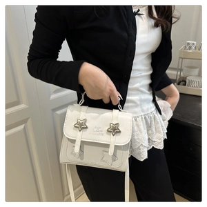 Detail of white square crossbody bag featuring star rivets and silver metal handle