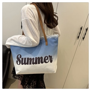 Detail of blue and white gradient canvas tote bag with Summer embroidery and leather handles