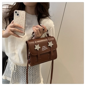 Detailed shot of a brown vintage crossbody bag featuring silver stars and decorative straps