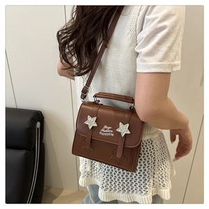 Detail of brown vintage crossbody bag featuring metal star buckles and fashion lettering