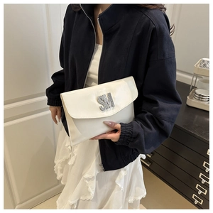 Close-up of white glossy envelope clutch with silver SM metal logo held by model