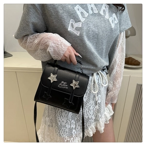 Detail of a black leather crossbody bag with silver stars and stylish text decorations