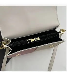 Detail of a color-block shoulder bag featuring a smooth gold zipper and pink leather panel