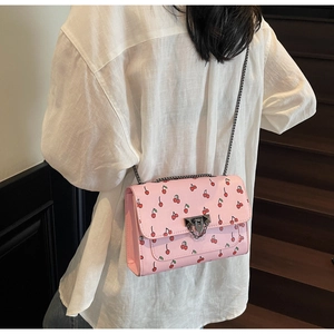 Detail of pink cherry print crossbody bag with silver rivet lock and chain strap