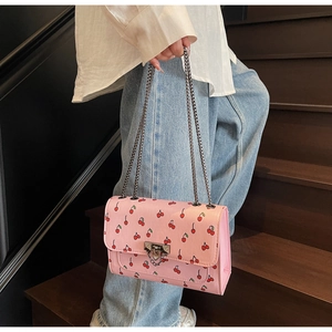 Close-up of pink cherry print crossbody bag with double chain strap and metal lock