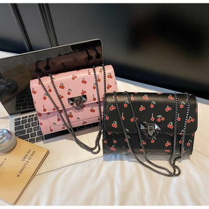 Detail of pink and black cherry print crossbody bags with metal chains and turn-lock