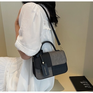 Detail of grey and black patchwork crossbody bag with gold hardware and top handle