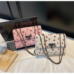 Detail of pink and white cherry print crossbody bags with chain straps and metal clasps