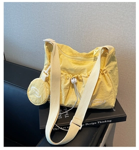 Detail of light yellow nylon pleated bag with round coin purse and wide strap