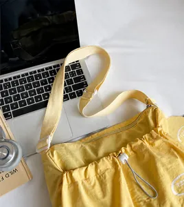 Détail à plat d'un sac bandoulière jaune texturé avec ordinateur et objets lifestyle