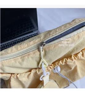 Gedetailleerde close-up van de soepele metalen rits op een gele geplooide nylon schoudertas