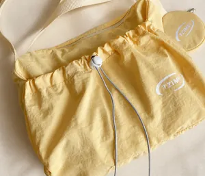 Détail du sac cabas en nylon jaune avec fermeture à cordon et texture de tissu plissé