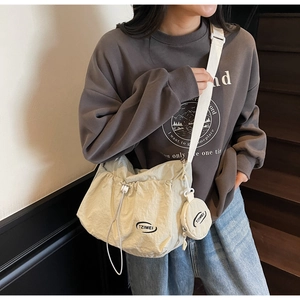 Detail of beige nylon shoulder bag featuring ruched design and small round coin purse