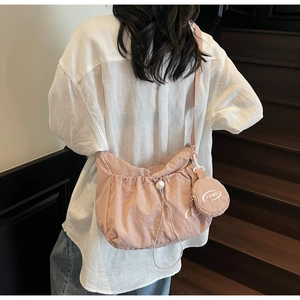 Detail of pink nylon shoulder bag featuring side coin purse and drawstring closure