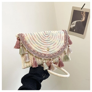 Detail of bohemian woven straw envelope bag with colorful embroidery and soft tassels