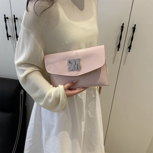 Pink glossy envelope clutch bag with rhinestone SM initials shown in hand by model