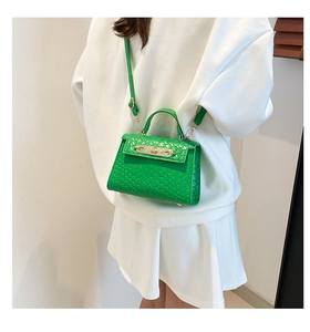 Close-up of green woven PU leather handbag with golden metal twist lock and texture