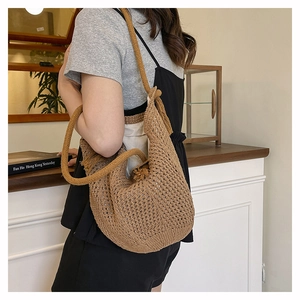 Detail of a brown knit shoulder bag with fringe tassel and thick rope knot handle strap