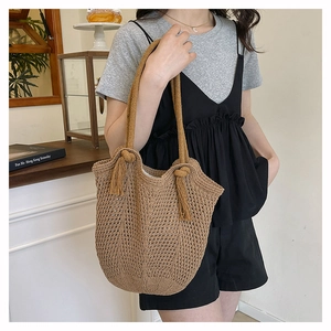 Detail of woven straw tote bag featuring hollow-out mesh texture and tassel knot strap