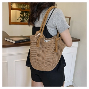 Close-up of brown knit shoulder bag with tassel details and hollow weaving texture