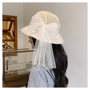 Detail of straw hat with white lace bow and delicate floral embroidery in cafe