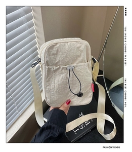 Detail of off-white wrinkled nylon crossbody bag with drawstring pocket and adjustable strap