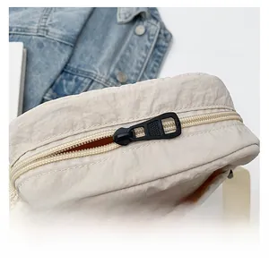 Detailed close-up showing the smooth zipper closure on the minimalist beige nylon bag