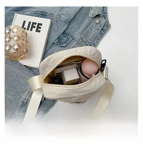 Top view showing storage capacity of the cream nylon crossbody bag for daily essentials