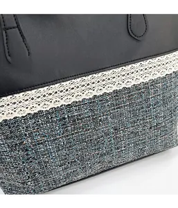 Detail of the stitching between black leather, lace trim, and tweed texture on a tote bag