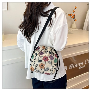 Detail of floral canvas bucket bag with drawstring closure and black shoulder strap
