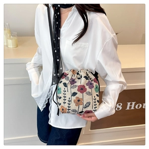 Detail of floral woven canvas bucket bag with drawstring closure and slim shoulder strap