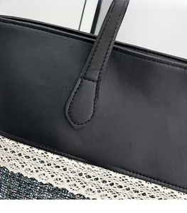 Detailed view of precision stitching on a black leather and lace patchwork tote bag