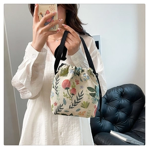 Detail of floral tapestry bucket bag with drawstring closure and woven handles