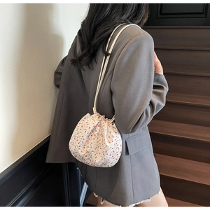 Floral drawstring bucket bag with pink roses and leather strap worn as a shoulder bag