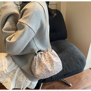 Detailed close-up of a white floral drawstring bucket bag with red flower patterns