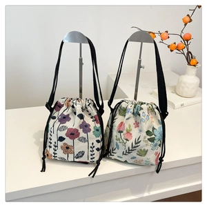 Detail of floral tapestry bucket bags with drawstring closure and black woven straps