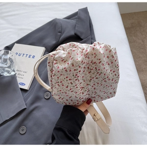 Detail of floral printed dumpling bag with elegant pleats and slim white leather strap
