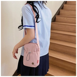 Detail of light pink mini nylon crossbody bag with drawstring closure and fashion tag