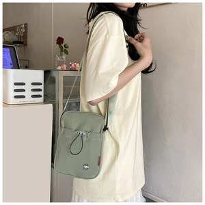 Close-up of sage green crossbody bag with drawstring pocket and adjustable wide strap