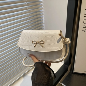 White crocodile embossed crossbody bag with golden bow and knotted strap on shoulder