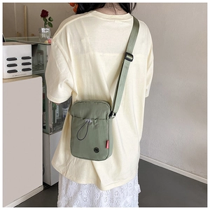 Outdoor crossbody nylon bag in sage green featuring an adjustable strap and drawstring detail