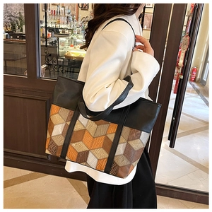 Detail view of large PU tote bag featuring geometric color-block patchwork on a model