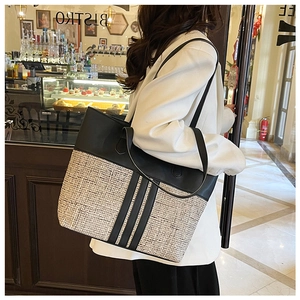 Detail of contrast stitch tote bag with woven texture and long black shoulder straps