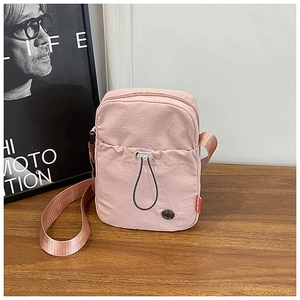 Close-up of pink nylon crossbody bag with pleated texture and woven drawstring details