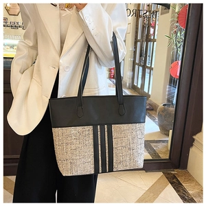 Detail view of large PU tote bag with black and beige contrast stitching worn by model