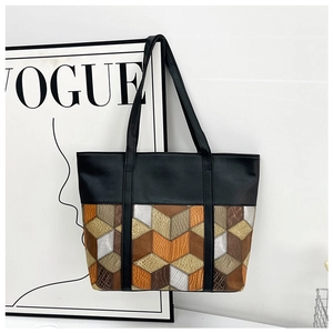 Detail of multi-color geometric block patchwork on a minimalist black PU leather tote bag